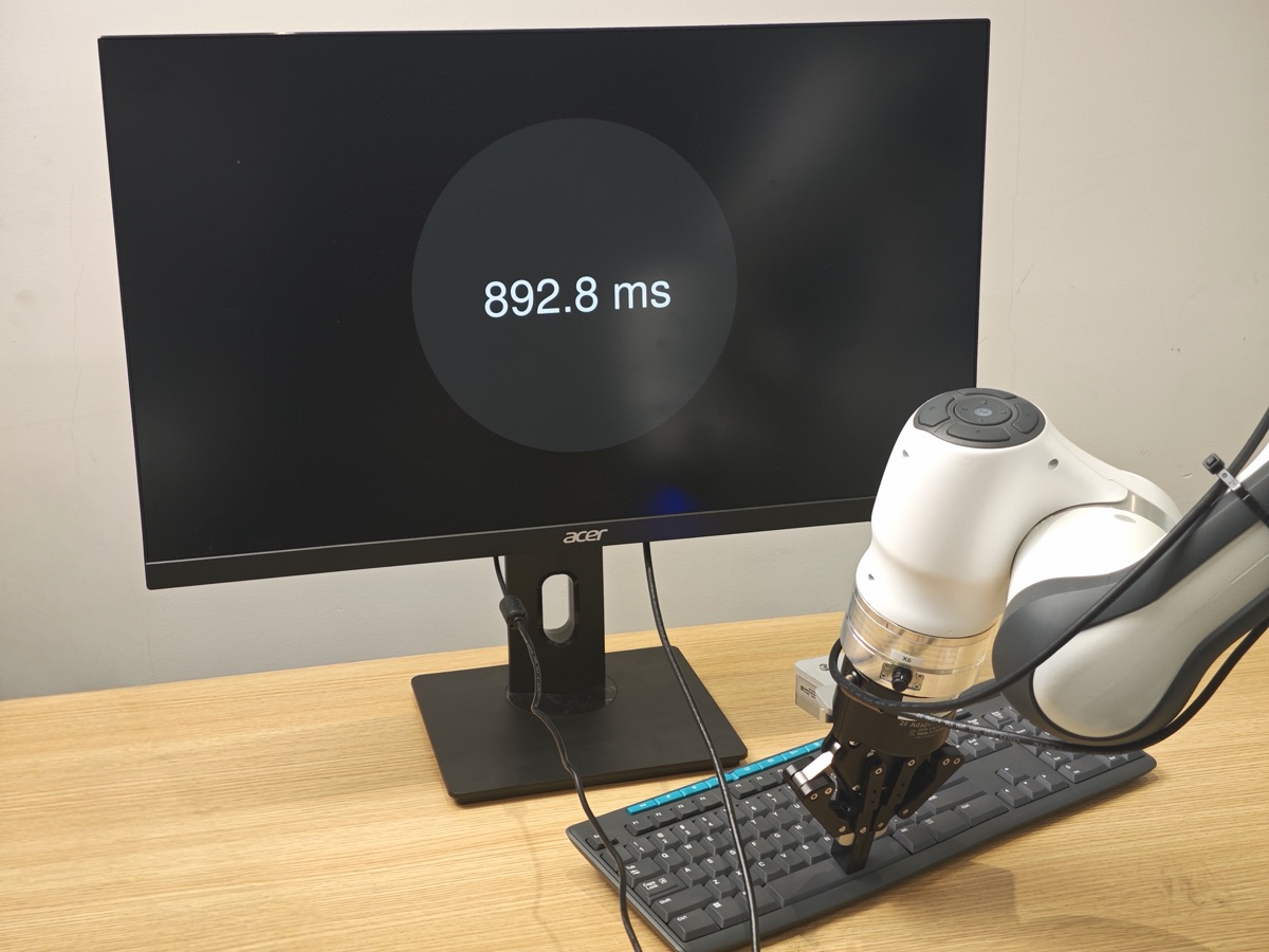 Robot presses the key; the measured latency is shown on screen.